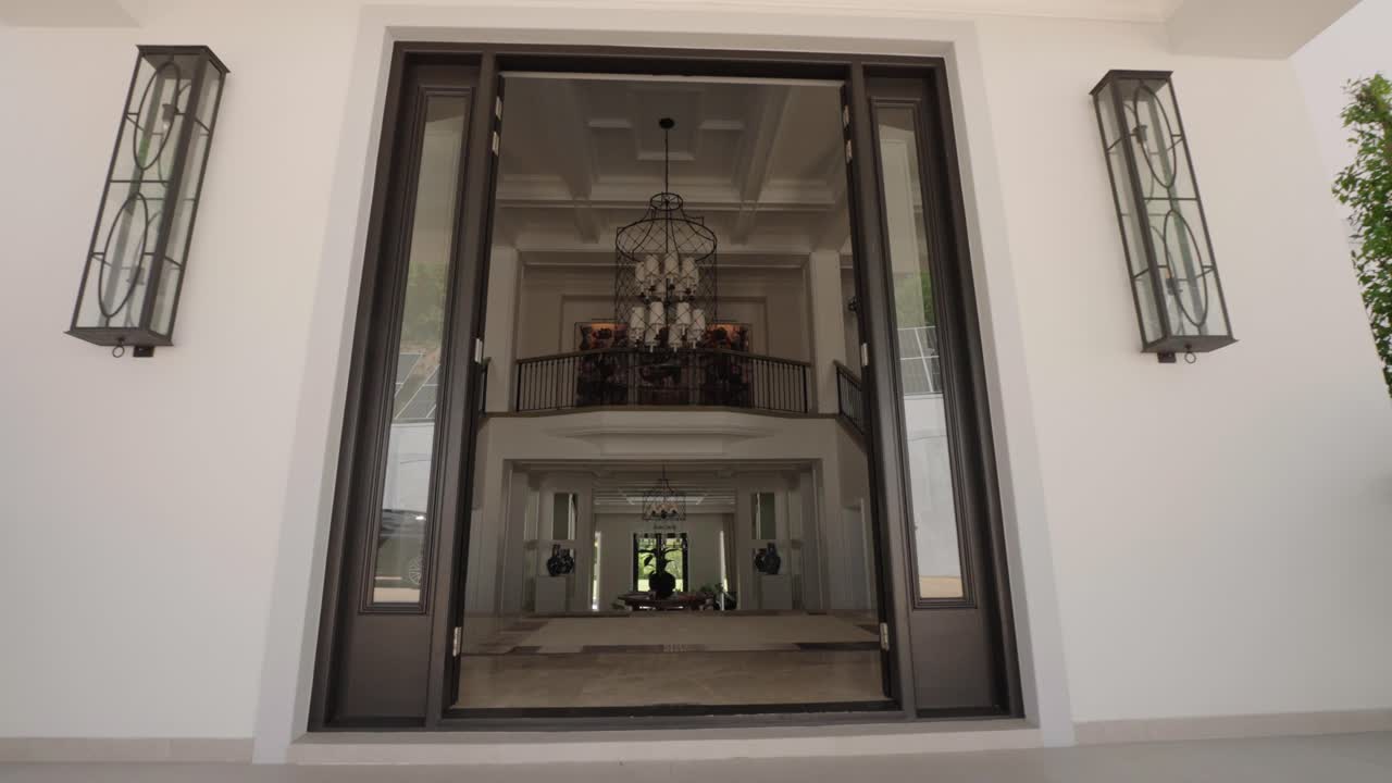 The entrance and hall to an expensive luxurious house with classy fixtures and a large staircase sprawling upwards from both sides of the entrance hall