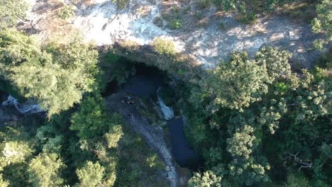 Drone-footage-of-waterfall-in-Chiang-Mai,-Thailand,-with-the-cliff-surrounded-by-trees