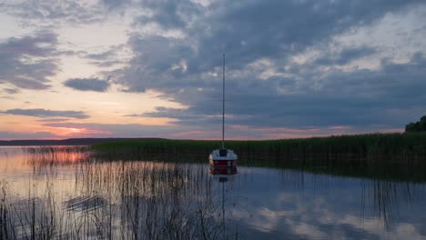 Sonnenuntergangshimmel-Zur-Goldenen-Stunde-Mit-Der-Spiegelung-Eines-Bootes-Im-See-Darunter