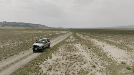 camino de tierra en la árida llanura de estepa en georgia y jeep conduciendo en él