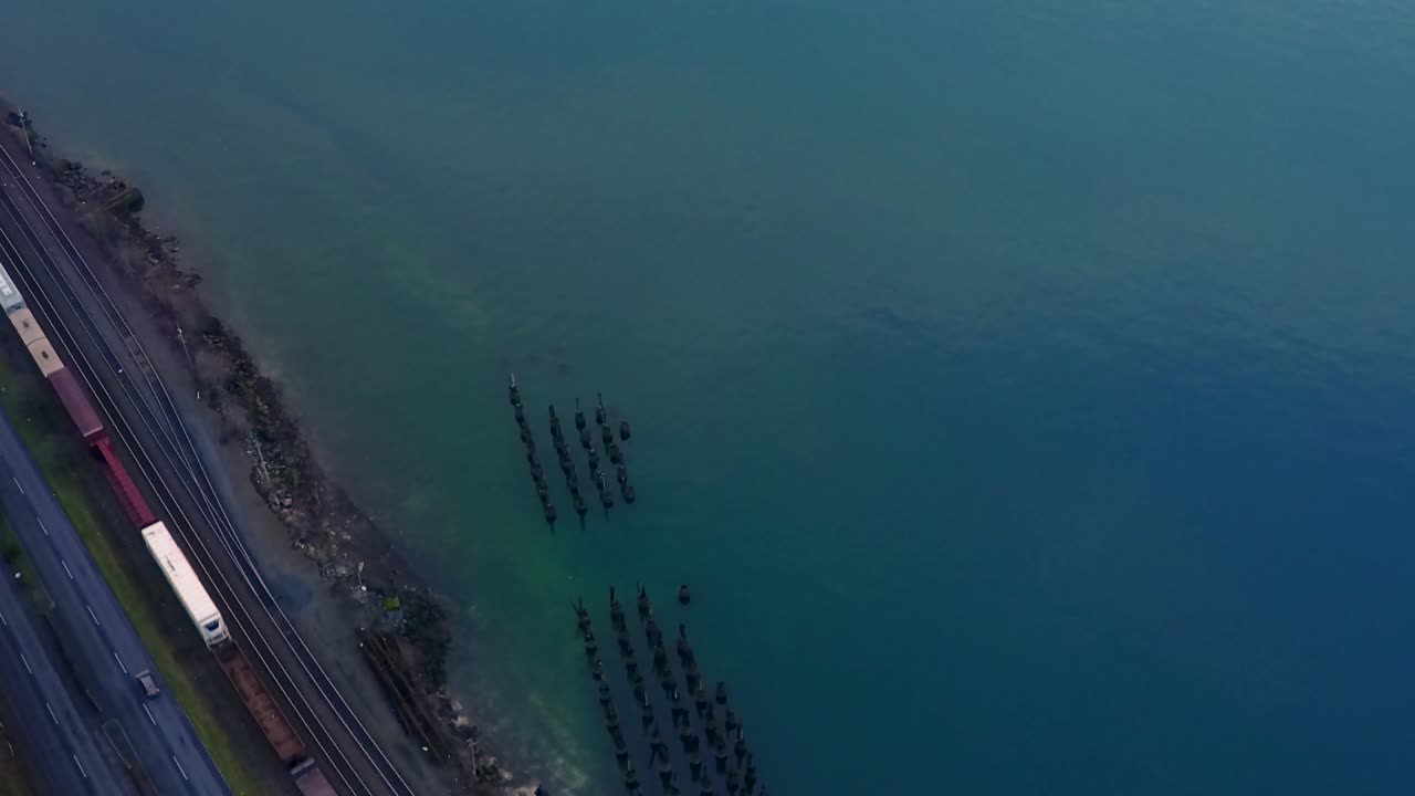 차분한 청록색 바닷물의 아름다운 풍경과 함께 미국 워싱턴의 만 옆에서 철도를 여행하는 기차 - 공중 촬영