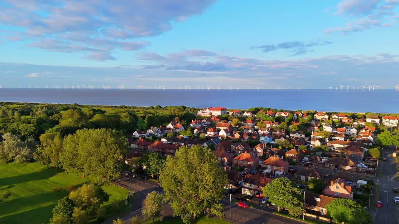 Aerial view of a coastal town with an offshore wind farm