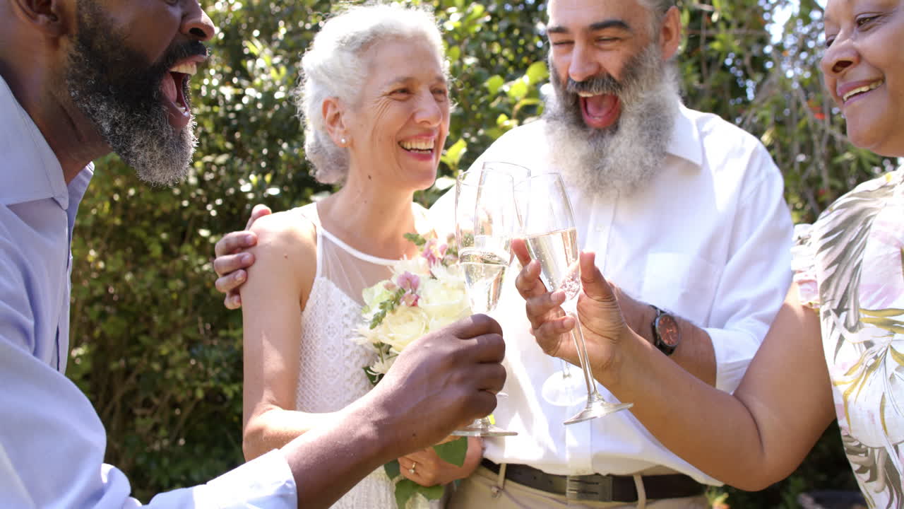Celebrating at outdoor wedding, senior friends toasting with champagne glasses, smiling together