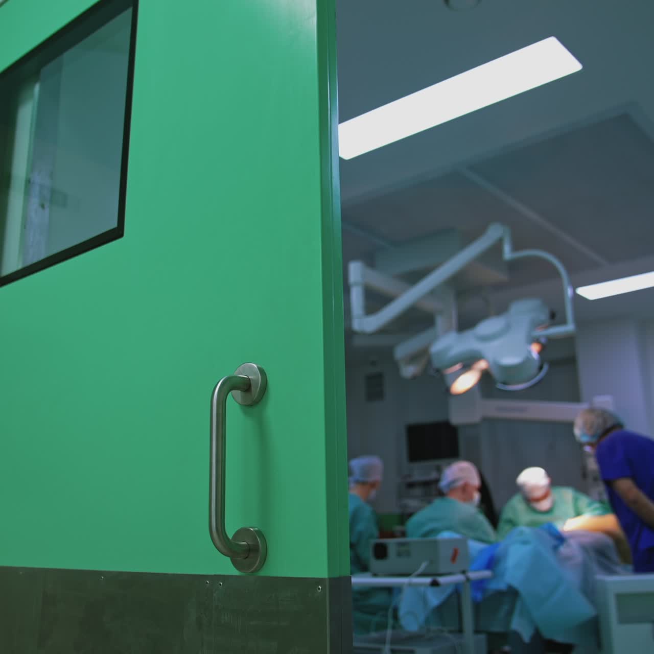Surgical room with group of plastic doctors. Blurred background of a surgical room from the door in clinic. View on the operating room from the hospital corridor