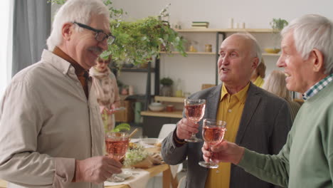 senior male friends drinking wine at home dinner party