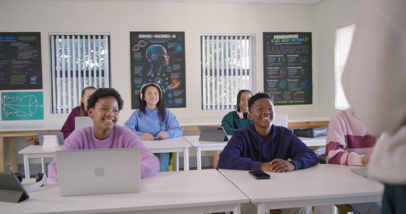 Aula di adolescenti eterogenea che guarda l'insegnante che insegna davanti, spostando l'attenzione dai laptop al monitor