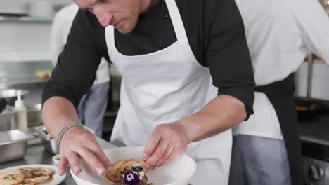 caucasian male chef decorating meal in kitchen, slow motion