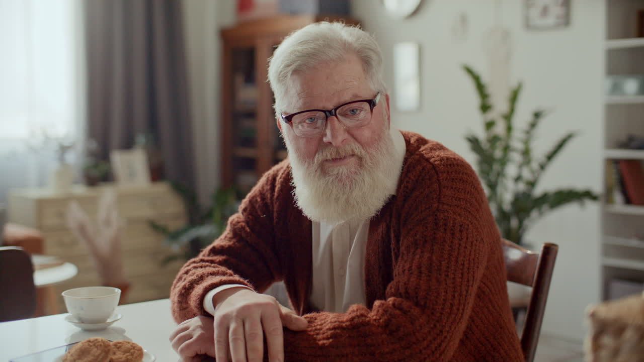 Elderly Man Sitting at Home, Talking to Camera via Video Call