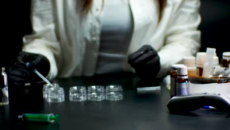 laboratory assistant in black gloves testing vaccine with pipette and pills on the side of the table