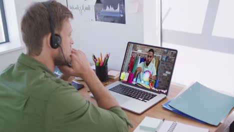 Hombre-Caucásico-Con-Auriculares-De-Teléfono-Haciendo-Una-Videollamada-Con-Un-Colega-Masculino-En-Una-Computadora-Portátil-En-La-Oficina