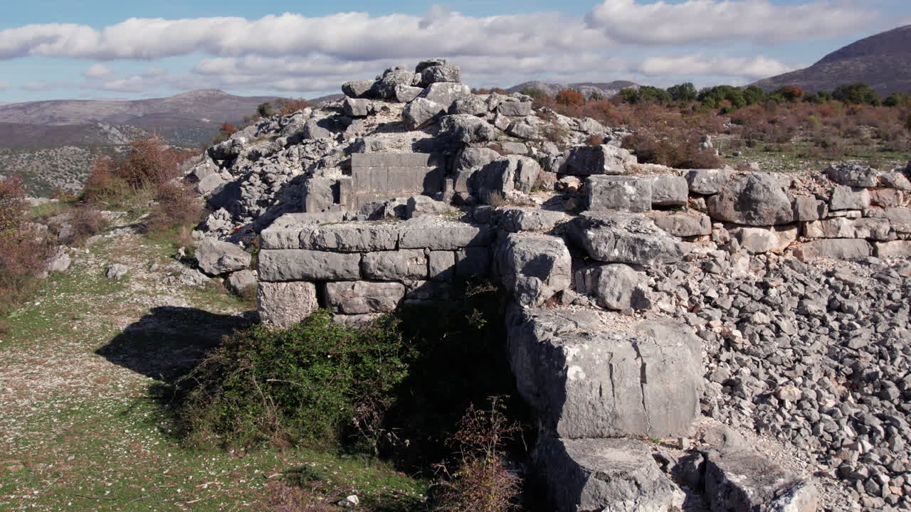 Close-up of Daorson’s curved Illyrian stone wall and stairs set against a rugged hillside, showing weathered blocks, rocky terrain, surrounding the ancient archaeological site near Stolac