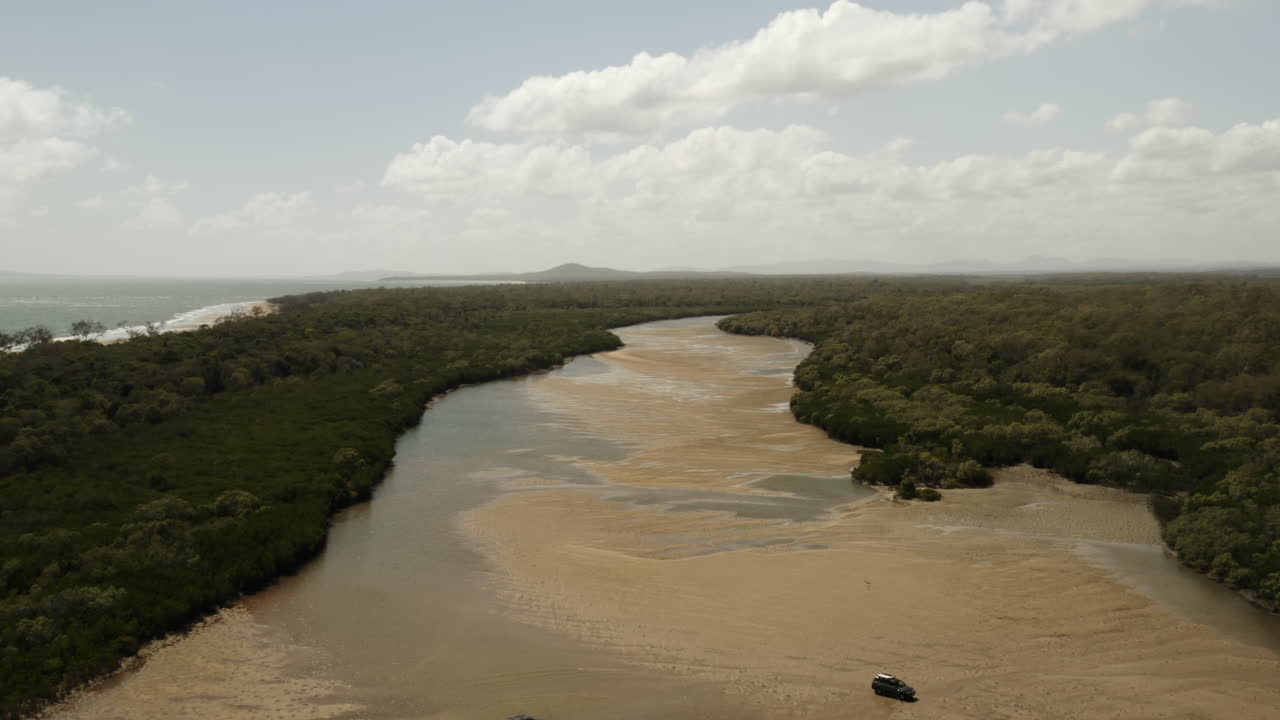 toma aérea hacia atrás de automóviles conduciendo en playas de arena y piscinas de agua rodeadas por el paisaje forestal de queensland en australia