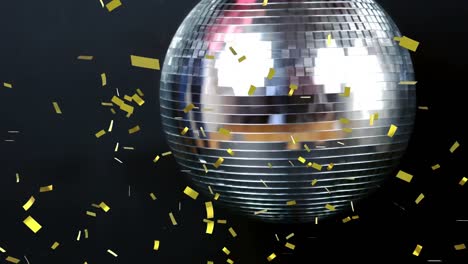 Golden-confetti-falling-over-silver-spinning-disco-ball-against-black-background