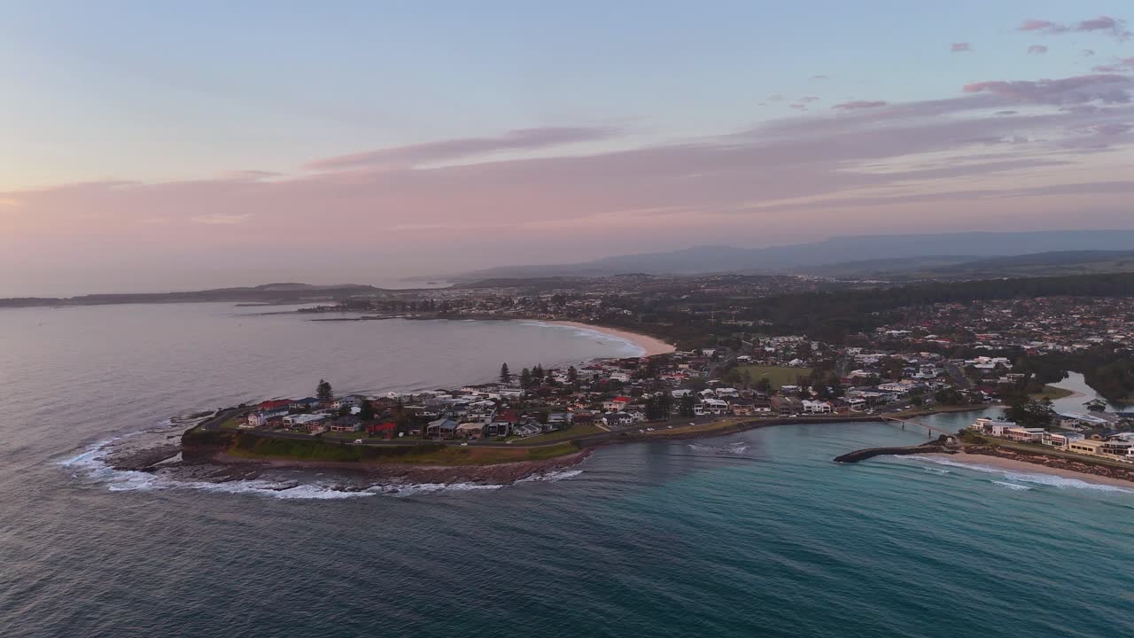 Sweeping aerial establishing orbit of Barrack Point coastline showing ocean, beach, and residential area