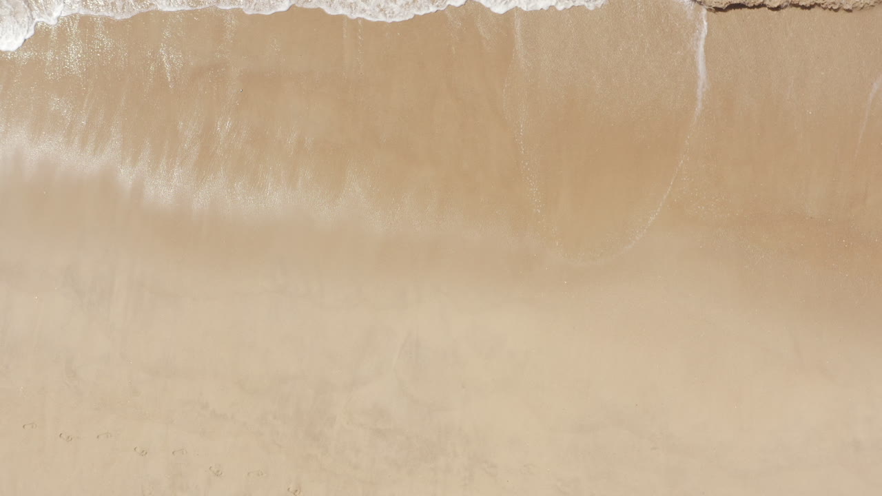 Vista aerea delle onde sulla spiaggia di sabbia dorata a Vale do Lobo, Algarve