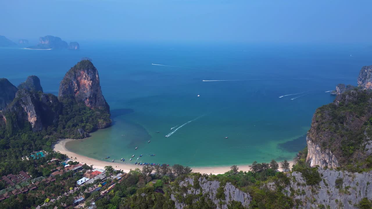 Railay Beach and Phra Nang Cave Beach in Krabi, Thailand, featuring limestone cliffs, turquoise water, and longtail boats. Wonderful aerial view flight fly reverse drone