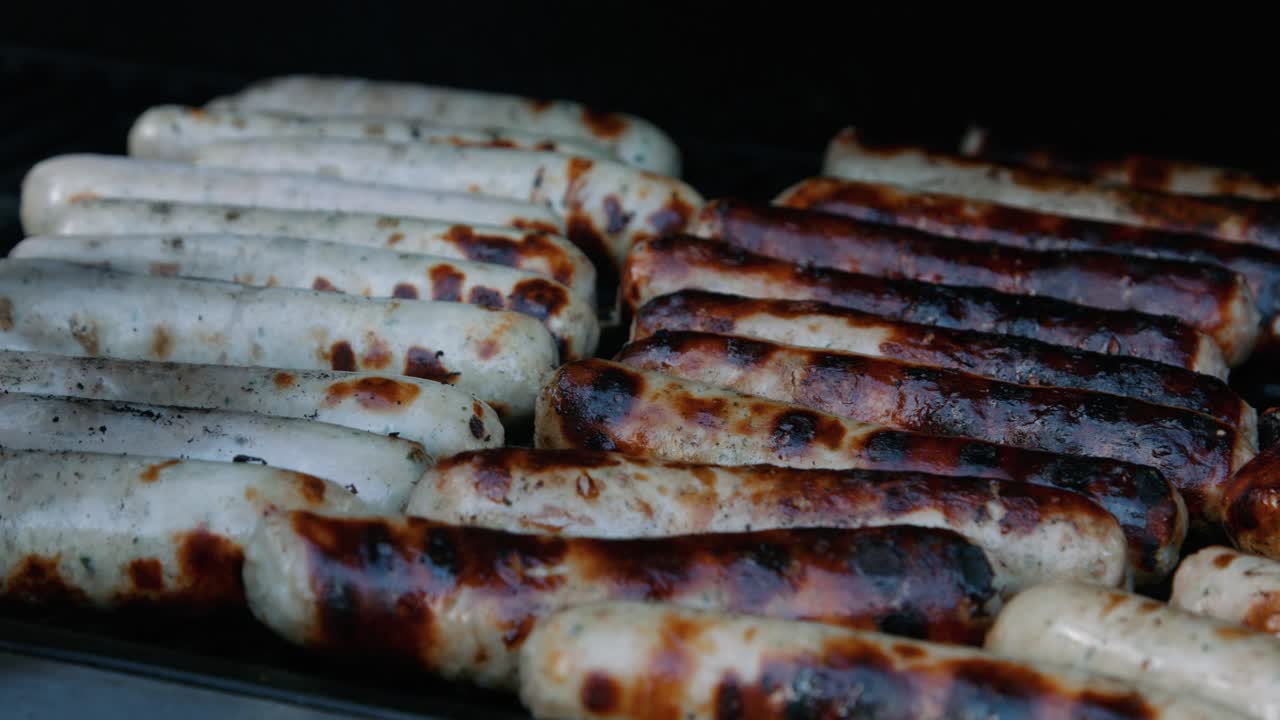 chef girando salchichas de cerdo en la barbacoa