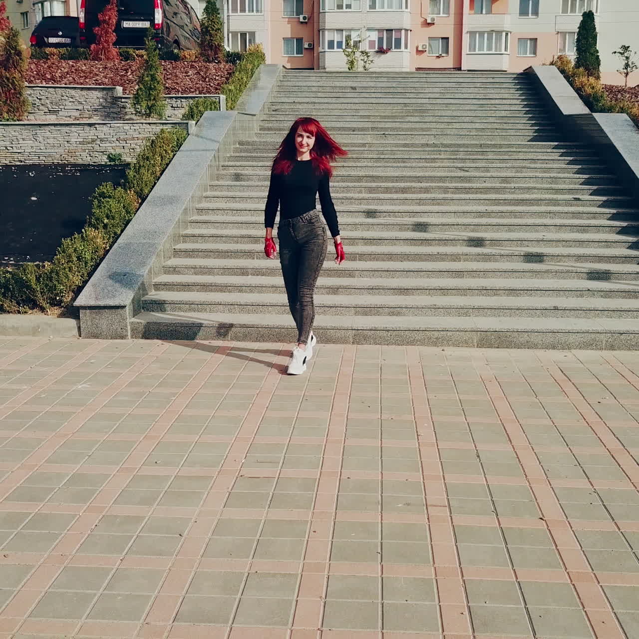 Young sexy woman wearing grey jeans and black shirt with red gloves goes to the new motorcycle. Happy female sitting on a red motorbike.