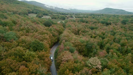 car driving on road winding through autumn forest in croatia, drone