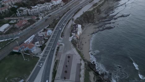 Wenn-Die-Sonne-über-São-Pedro-Do-Estoril-Aufgeht,-Befahren-Autos-Die-Küstenstraße-Und-Schaffen-Eine-Malerische-Szene,-In-Der-Sich-Das-Licht-Der-Morgendämmerung-Mit-Dem-Täglichen-Rhythmus-Des-Lebens-Vermischt