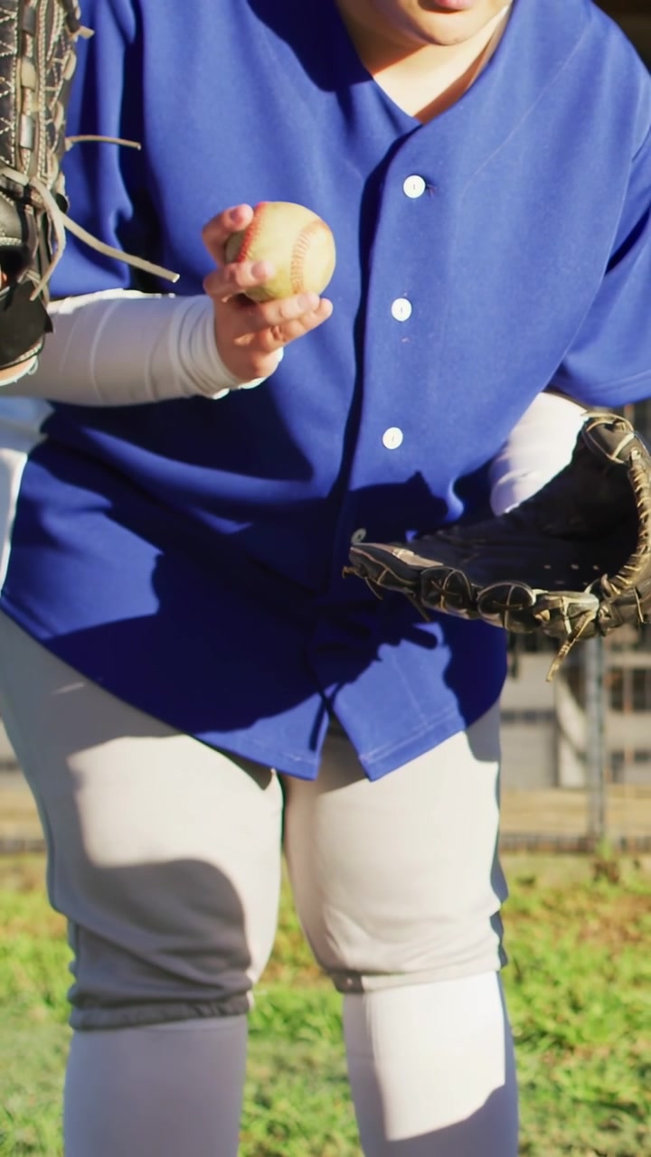 Video verticale: Giocatrice che sistema il guanto, poi ruota la palla da baseball sul campo preparandosi a lanciare