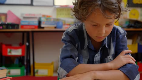 front view of caucasian schoolboy studying on desk in classroom at school 4k
