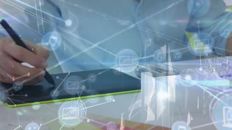 animation of network of digital icons over mid section of male graphic designer using graphic tablet