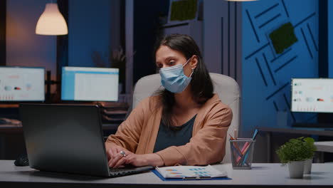 workaholic businesswoman with face mask against covid19 working in startup office