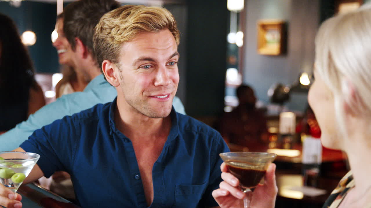 데이트 중인 젊은 커플이 테일 바에서 술을 마시고 건배합니다.
