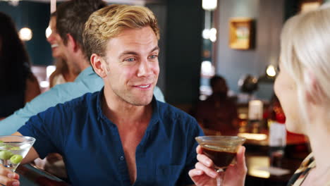 young couple on date meeting for drinks in cocktail bar and making a toast