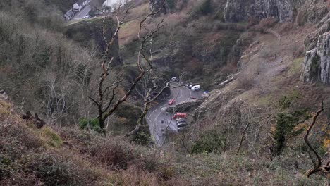 conducción de automóviles rojos y tejiendo a través del paisaje del valle del desfiladero de cheddar en la ciudad rural de cheddar en somerset, inglaterra