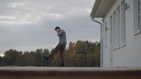 static view of man on a terrace talking on mobile while kicking stones