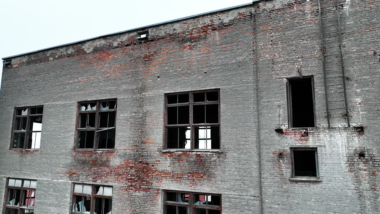 Old brick factory building. Coming closer to the house with broken windows, empty inside. Blue sky backdrop.