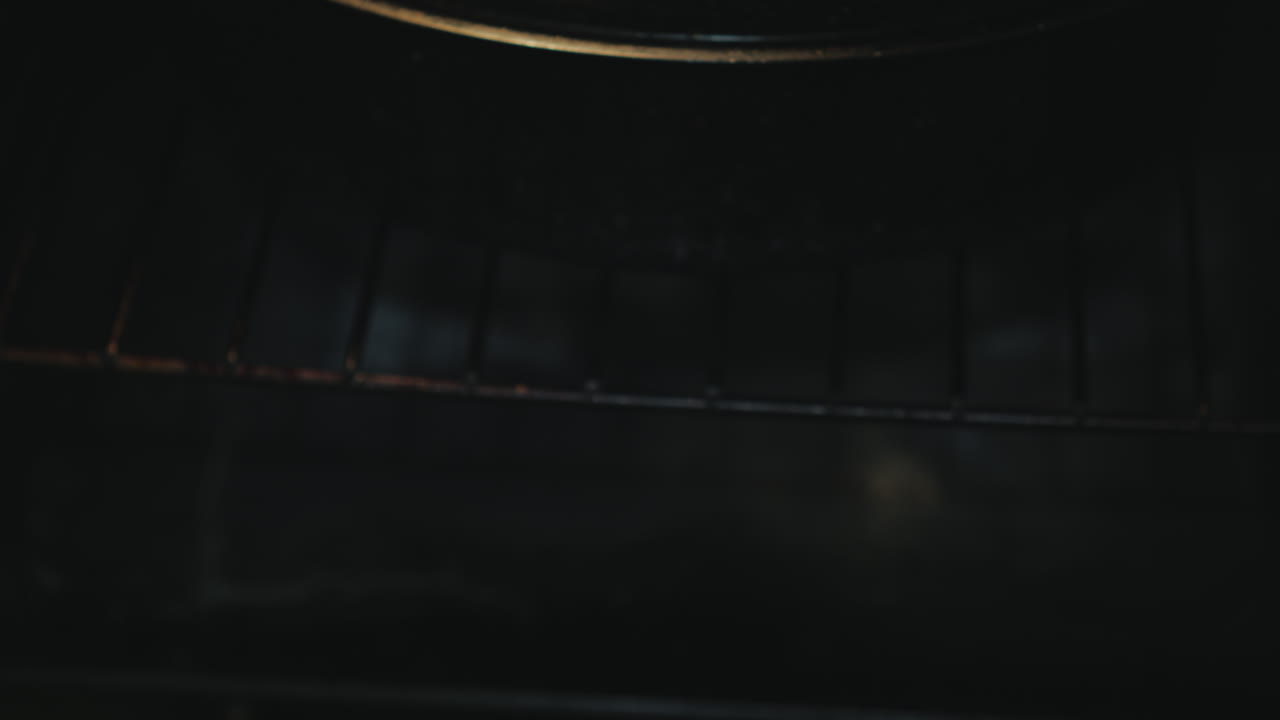 장갑을 낀 여자가 아침에 감자를 튀기는 로스터의 뚜껑을 엽니다