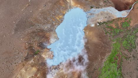 an aerial drone's ascending view from engjahver's steam lake on the reykjanes peninsula in iceland