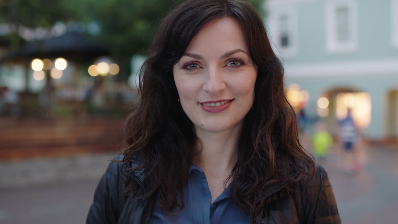 ritratto ravvicinato di una donna felice ed elegante che sorride alla telecamera godendo di una tranquilla serata urbana