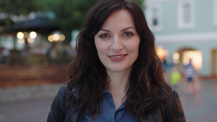 ritratto ravvicinato di una donna felice ed elegante che sorride alla telecamera godendo di una tranquilla serata urbana