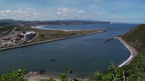 overcast sky above a coastal port view with calm water and hills in the distance