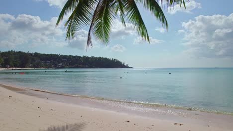 4k-Aerial-Drone-Footage-Stable-of-Salad-Beach-on-Koh-Phangan-in-Thailand-with-Palm-Leaves,-Fishing-Boats,-Teal-Water,-Coral,-and-Green-Jungles