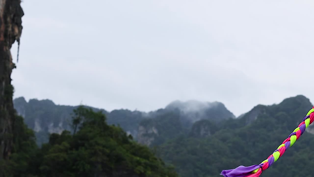 Vibrant boat ornaments sway gently with mist-covered mountains in the background, creating a serene and picturesque scene.