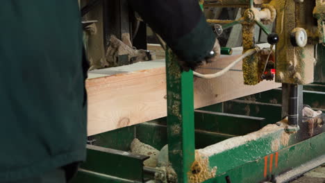 sawing plank from a log in old dirty sawmill by electrical bandsaw