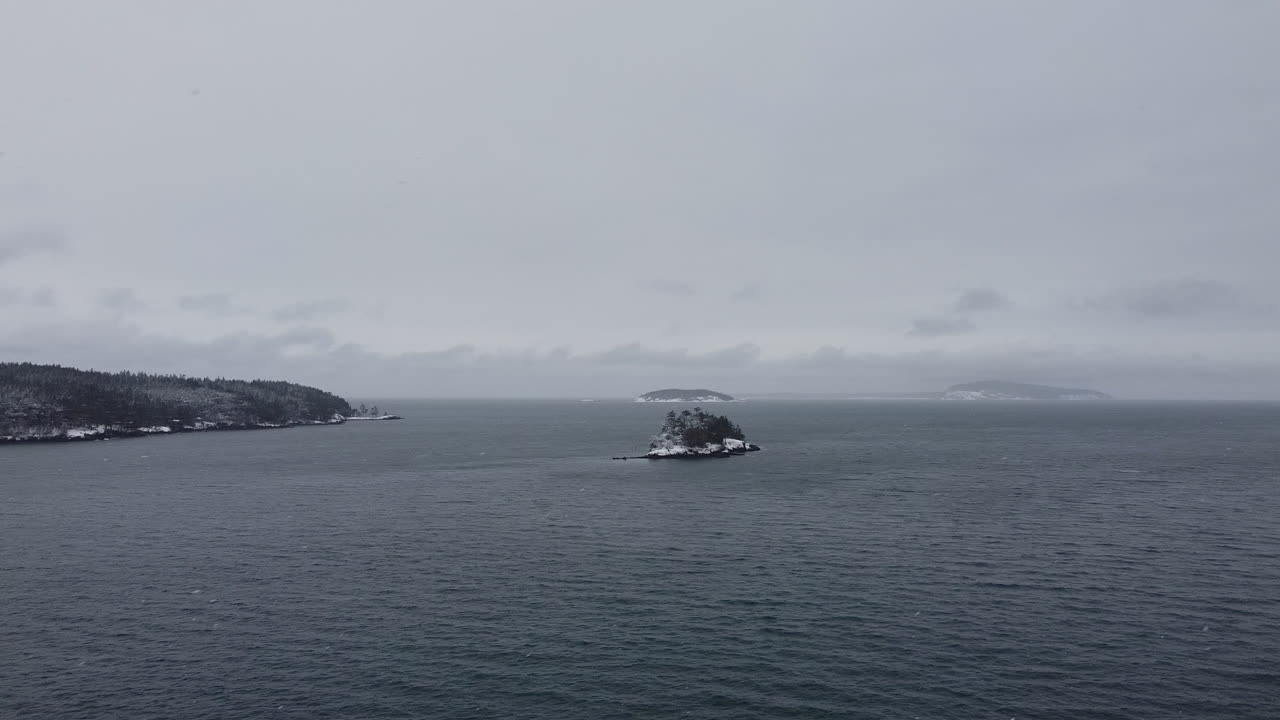 панорамный вид на море, островок и горы в гавани фрайдей во время снегопада на острове сан-хуан, штат вашингтон