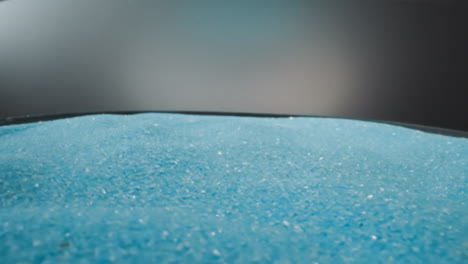 bright blue sand crystals lie in thin layer on loud speaker