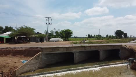 Dron-Flying-Away-From-Bridge-Over-Irrigation-Canal-In-Countryside-Of-Battambang,-Cambodia