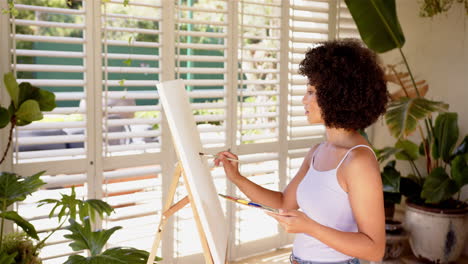 painting on canvas, woman holding palette and brush in bright room