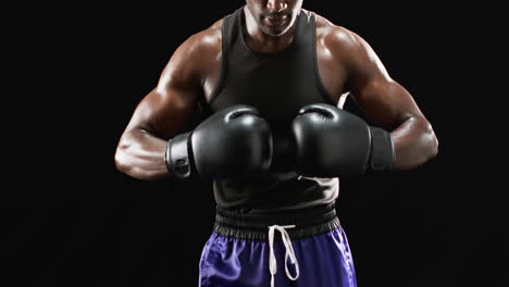 african american boxer in boxing gear poses confidently on black background