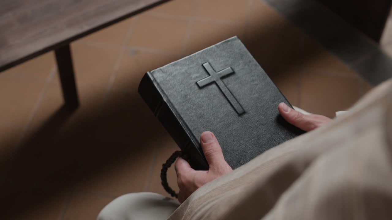 A person holding a Bible and rosary in church