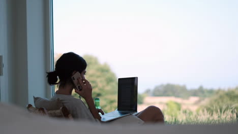 woman in relaxed attire working from home using laptop and smartphone