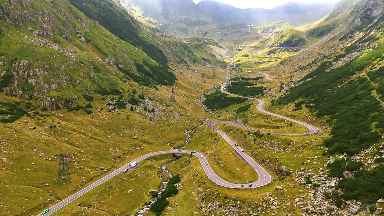 Winding serpentine of the Transfagarasan highway with cars. The Transfagarasan road in Romania with serpentine turns and moving cars among the mountains