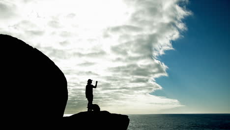 Silhouette of a person standing on a cliff overlooking the ocean